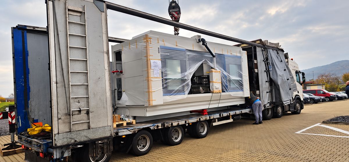 In weißer Schutzfolie verpacktes Trocknergehäuseteil, mit Ketten auf einem Spezialauflieger gesichert